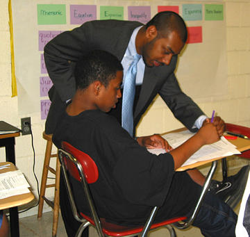 A teacher helping a student with an assignment at his desk